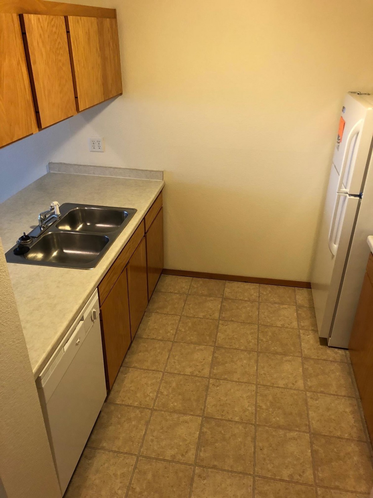 A compact kitchen with wooden cabinets, a sink, and tiled flooring.