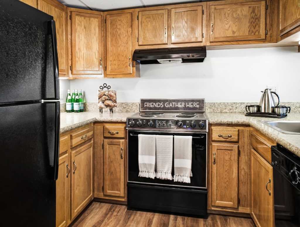 A cozy kitchen with wooden cabinets and black appliances, featuring a stove and refrigerator.