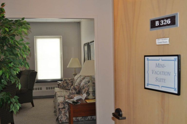 A view into a living room through an open door, showcasing furniture and natural light from a window.