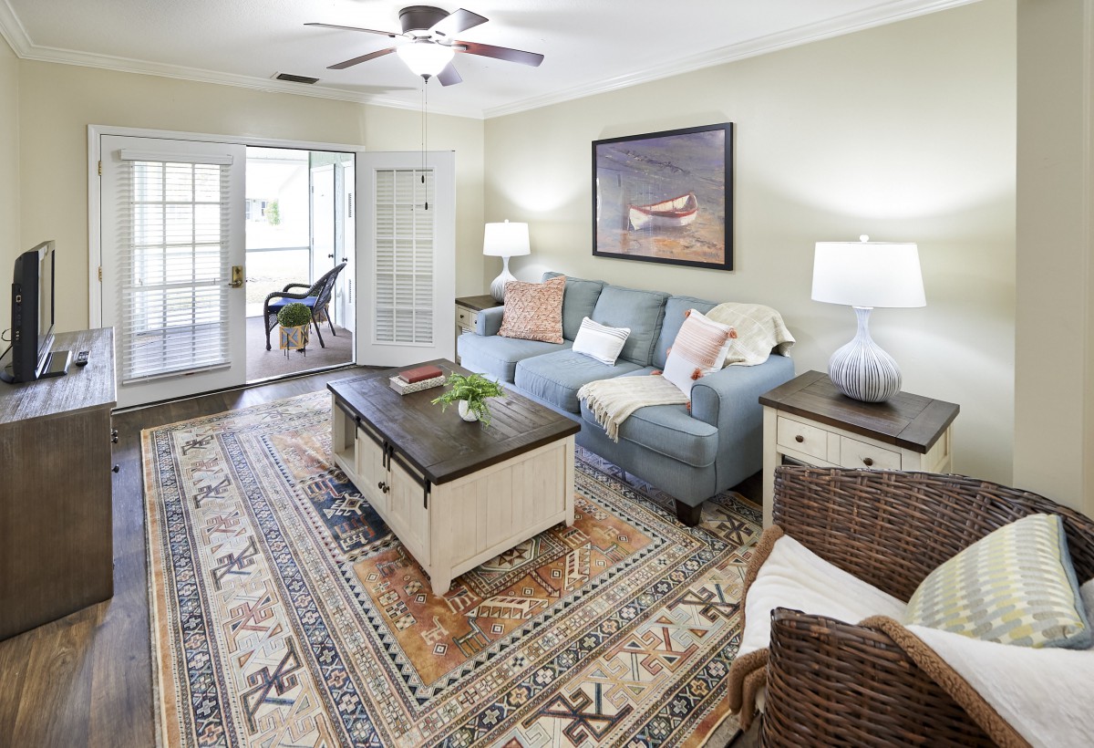 A cozy and well-decorated living room with a blue sofa, patterned rug, and wooden coffee table.