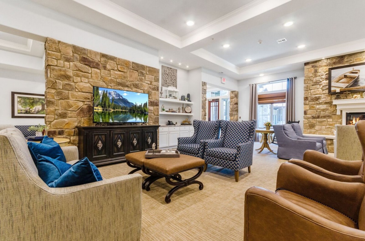A modern living room featuring a stone wall, comfortable seating, and a large television.