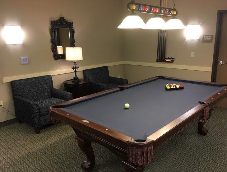 A cozy billiard room featuring a pool table with accompanying furniture and decor.