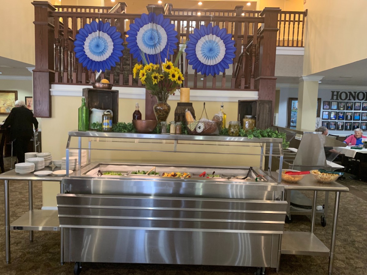 A dessert display case inside a decorated indoor setting with sunflowers and awards.