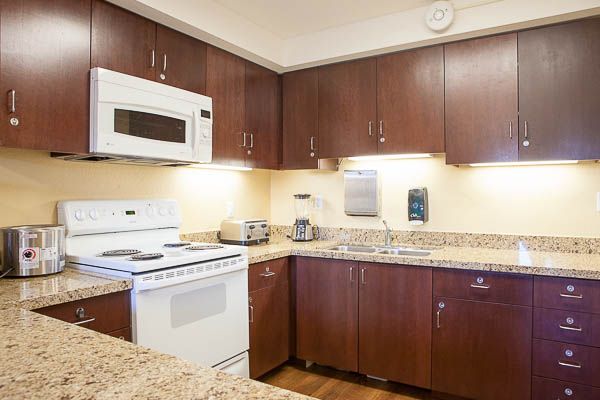 A modern kitchen with wooden cabinets, granite countertops, and various appliances.