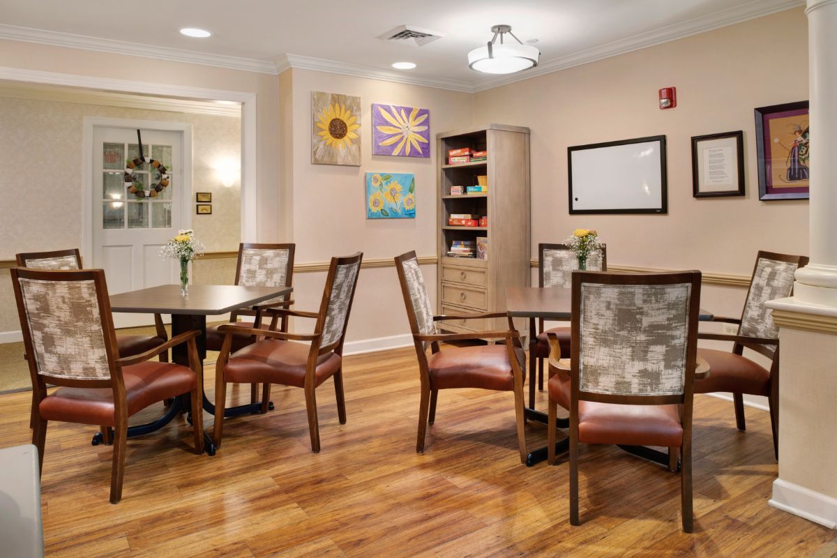 A cozy dining area featuring wooden tables and chairs, decorated with colorful artwork on the walls.