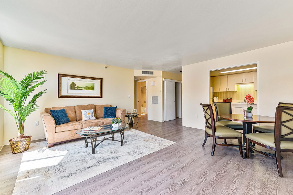 A modern living room with a sofa, coffee table, and dining area adjacent to a small kitchen.