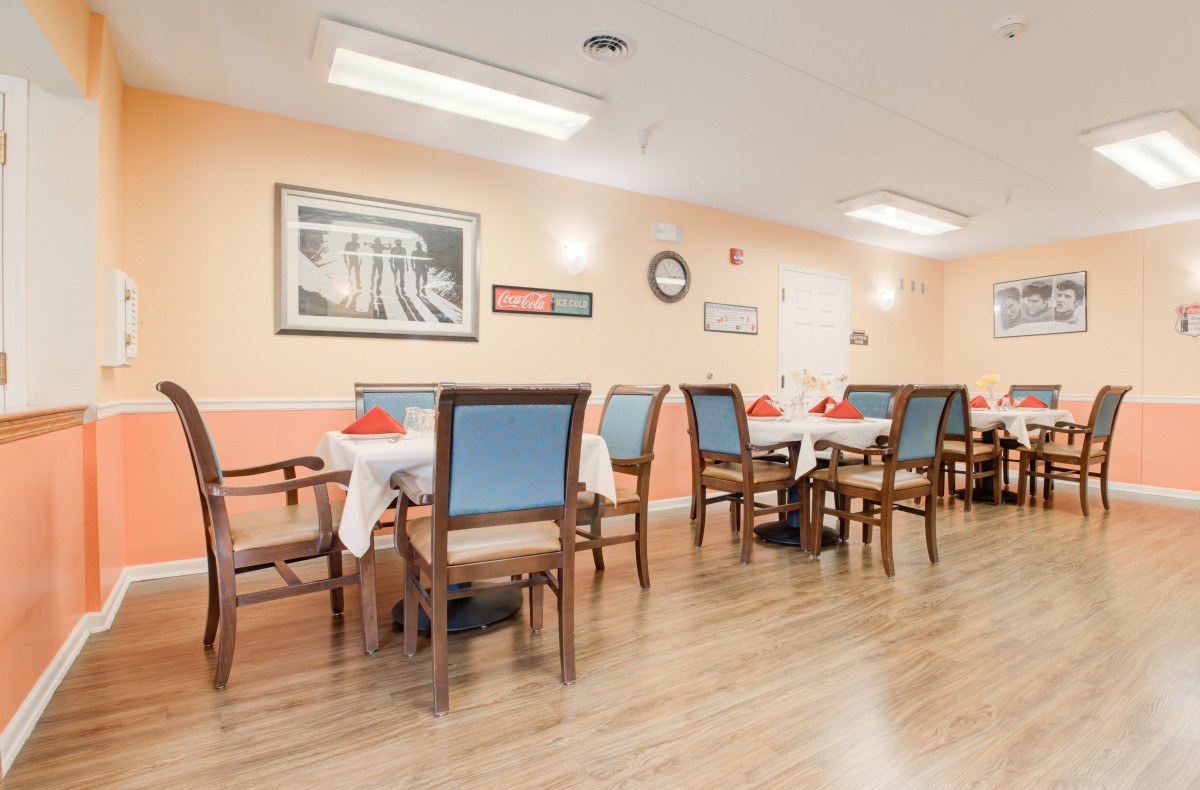 A cozy dining room with neatly arranged tables and chairs, adorned with wall art and warm lighting.