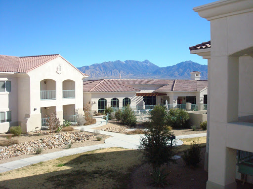 A serene view of a courtyard surrounded by buildings, with mountains in the background under a clear blue sky.