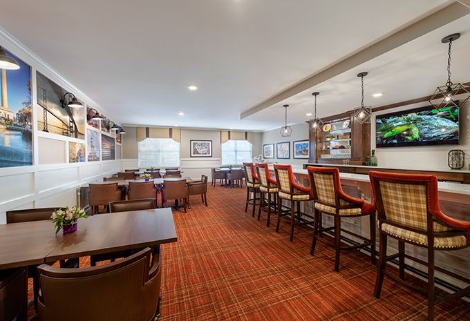 A modern restaurant interior featuring a seating area with tables, chairs, and a bar counter with stools.