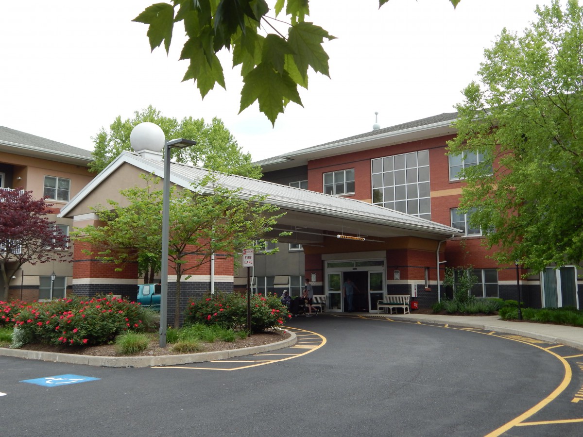 Entrance of a brick hospital building surrounded by trees.