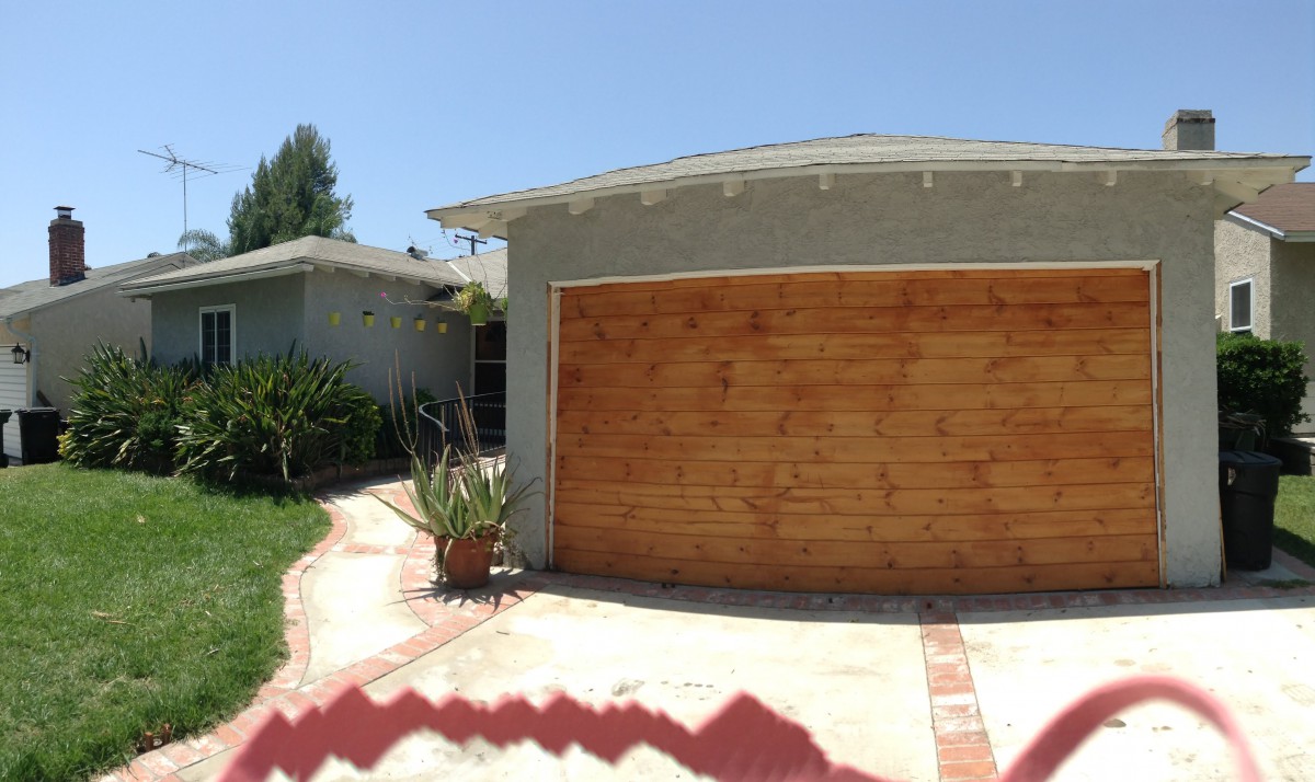 A residential house with a wooden garage door and a paved driveway.