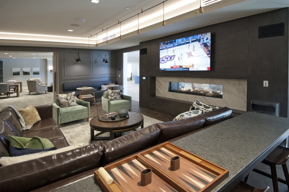 A modern lounge area featuring a large TV, comfortable seating, and a game board on the table.
