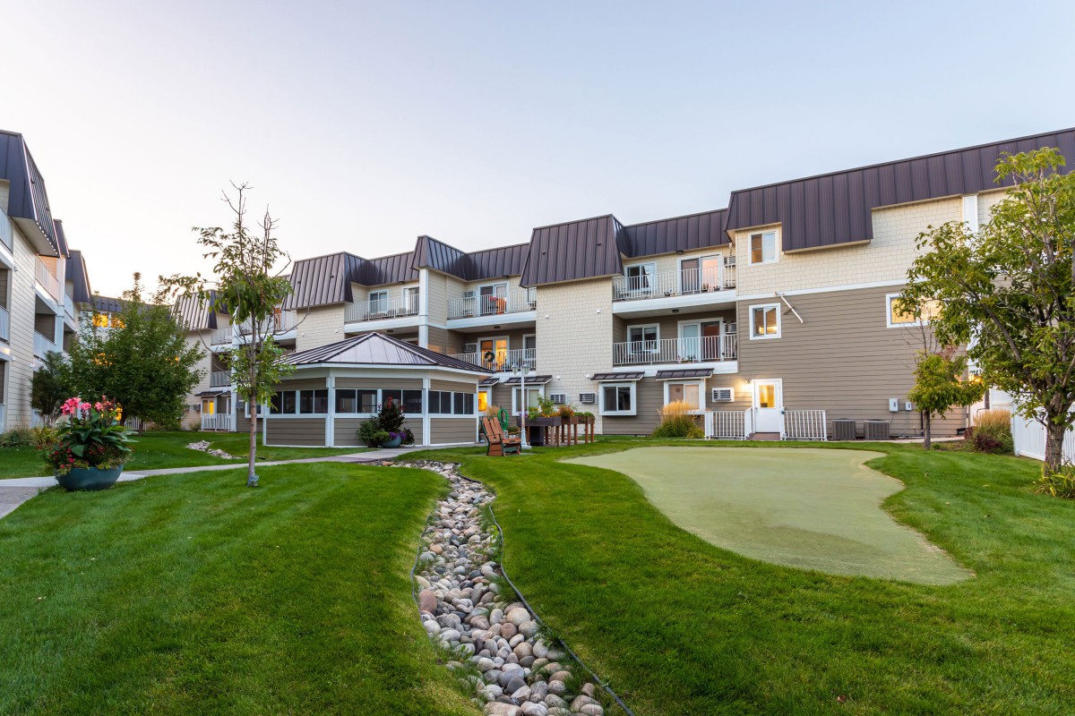 A modern apartment building with a well-maintained lawn and outdoor patio area.