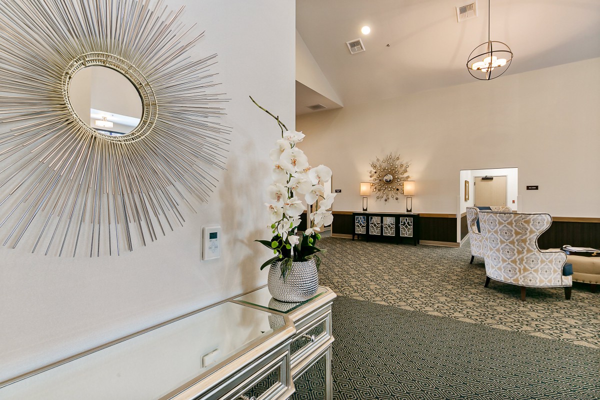 An elegant hallway with ornate decorations, featuring a mirror and floral arrangement.