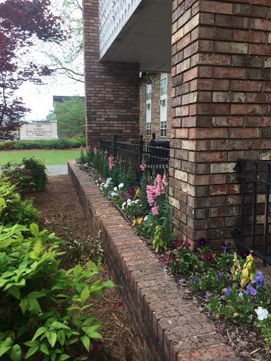 A beautifully landscaped garden with a variety of colorful flowers along a brick wall.