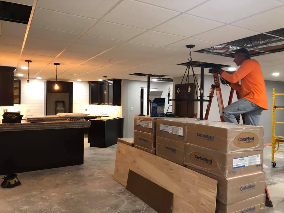 A worker installing lights in a kitchen under renovation.