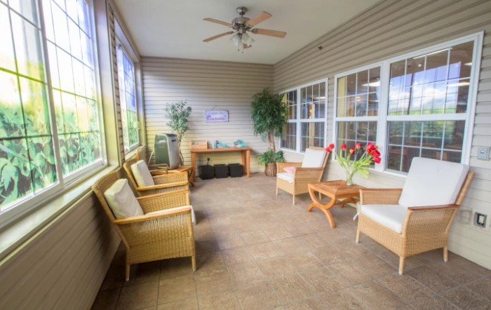 A cozy sunroom featuring comfortable seating, large windows, and decorative plants.