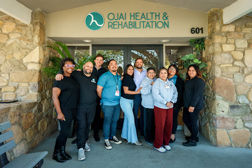 Staff members of Quai Health & Rehabilitation pose for a group photo outside their facility.