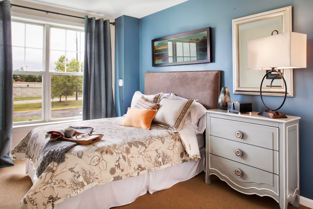 A cozy bedroom with blue walls, a well-decorated bed, and a stylish nightstand.