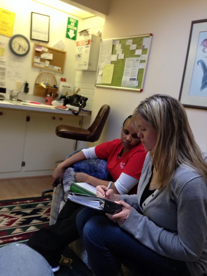 Two women are sitting and writing in an office space.