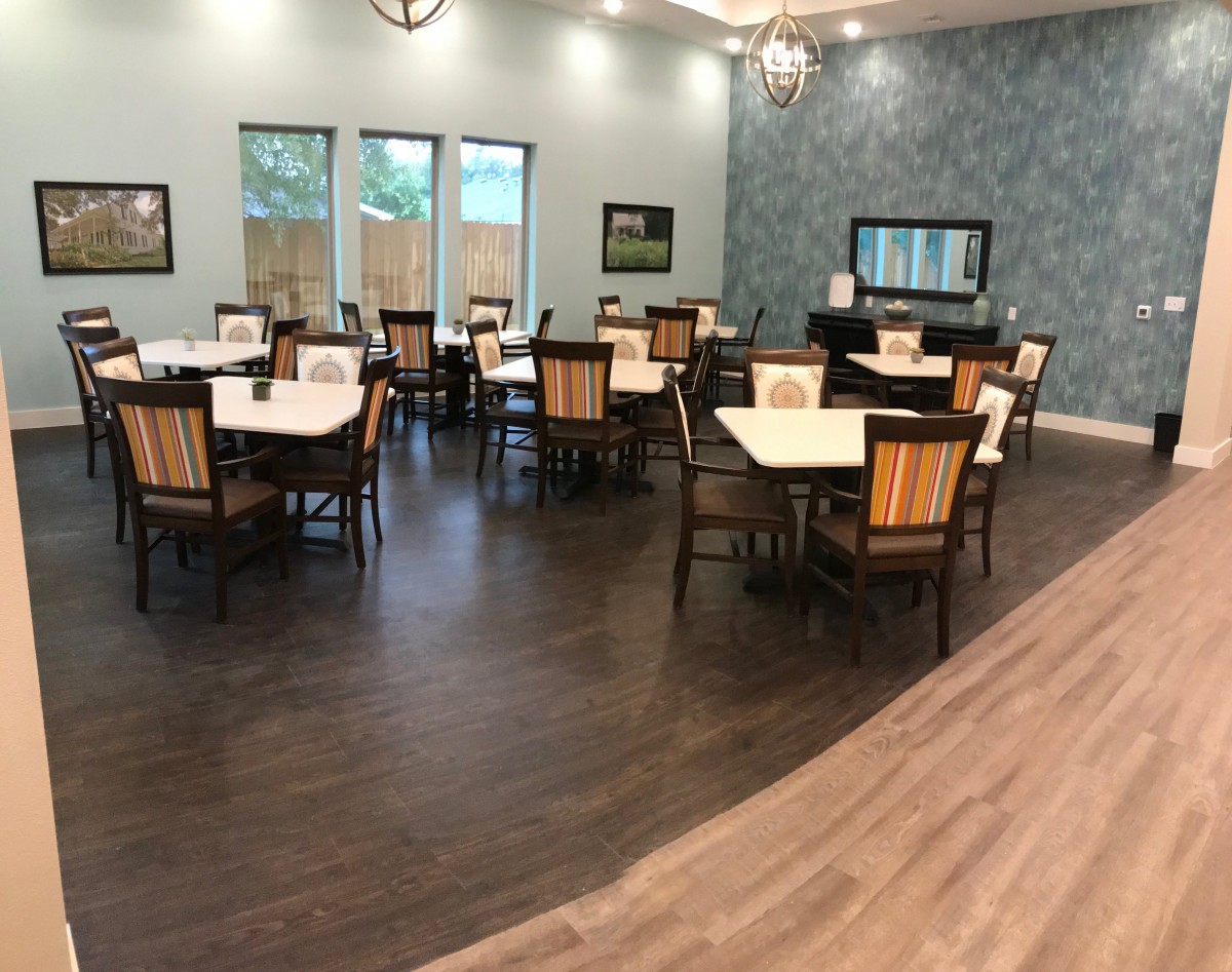 An empty dining room with neatly arranged tables and chairs, featuring elegant interior design and wood flooring.