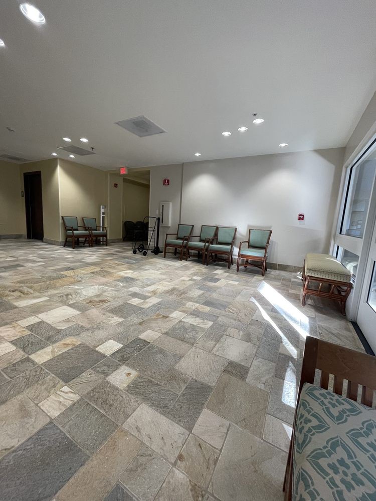 An empty waiting room with chairs lined against the wall and tiled flooring.