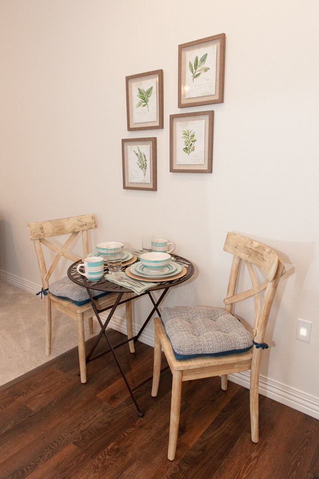 A cozy small dining area with a table set for two, featuring wall art decor.
