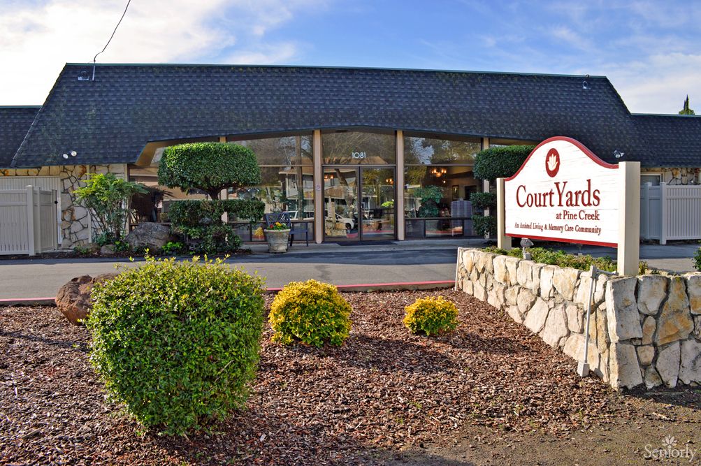 A well-maintained storefront with manicured bushes and a prominent sign at the entrance.
