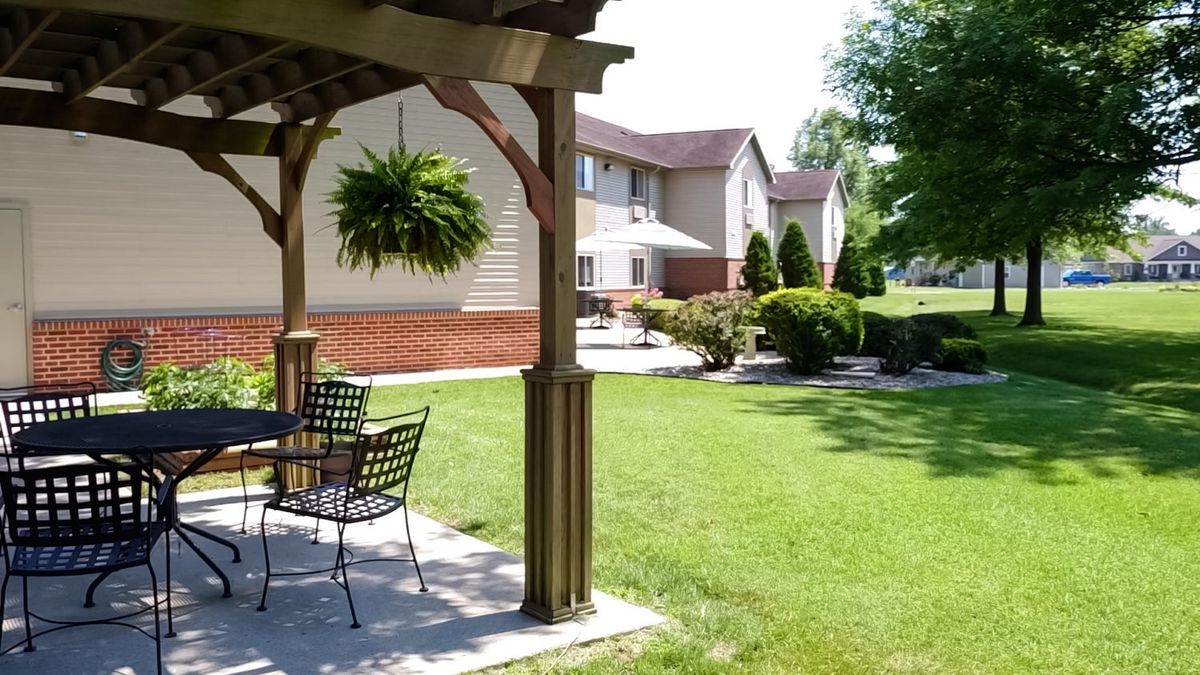 A well-maintained patio area with outdoor seating and greenery at an apartment complex.