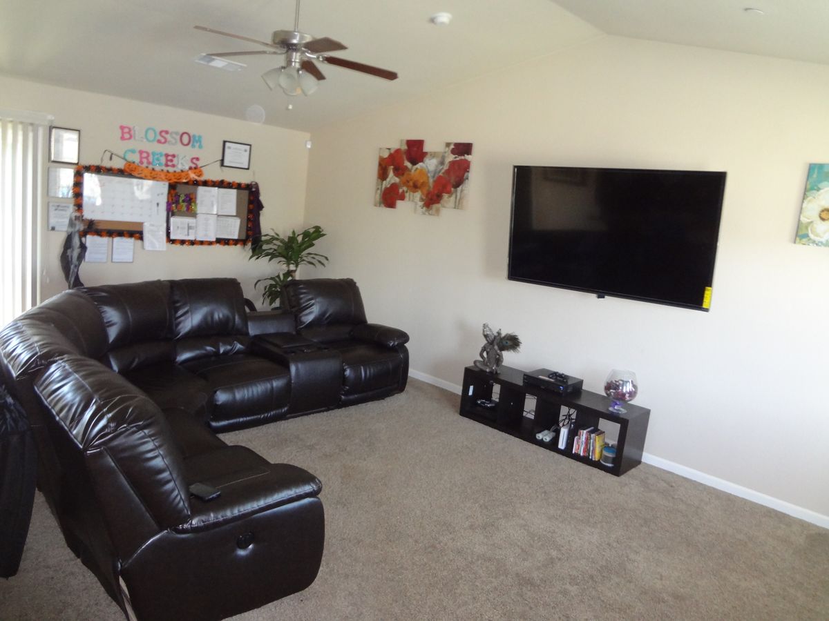 A cozy living room with a leather couch, large TV, and modern decor.