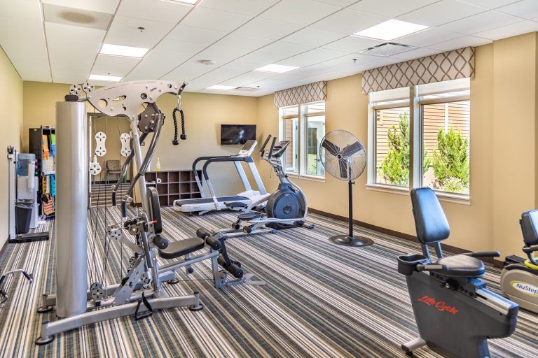 A well-equipped gym with modern exercise machines and a bright, spacious interior.