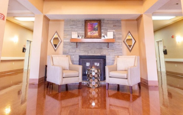 A cozy living room with two chairs flanking a fireplace, featuring elegant decor and warm wooden flooring.