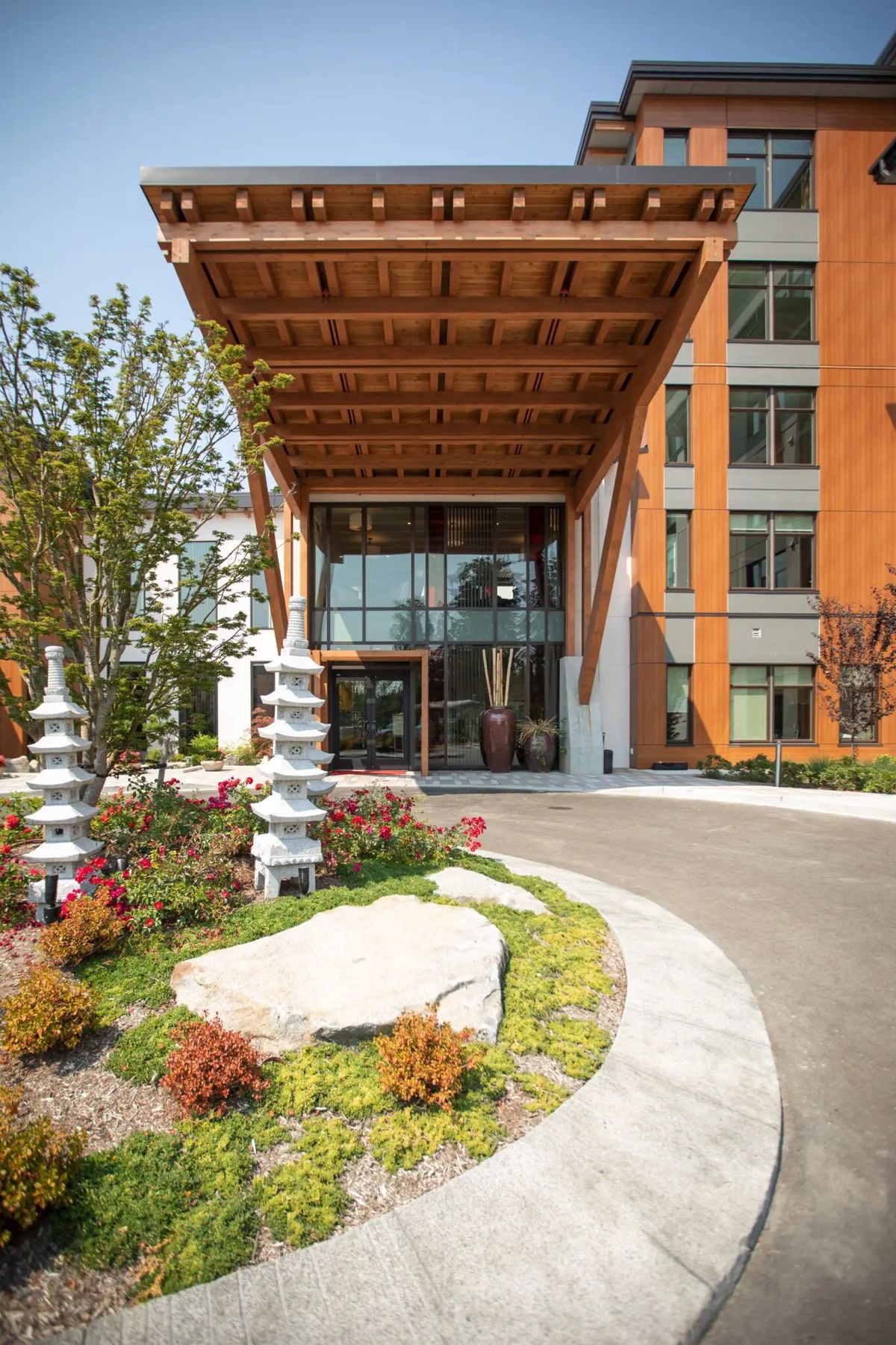 A modern building entrance with wooden overhang and landscaped gardens.