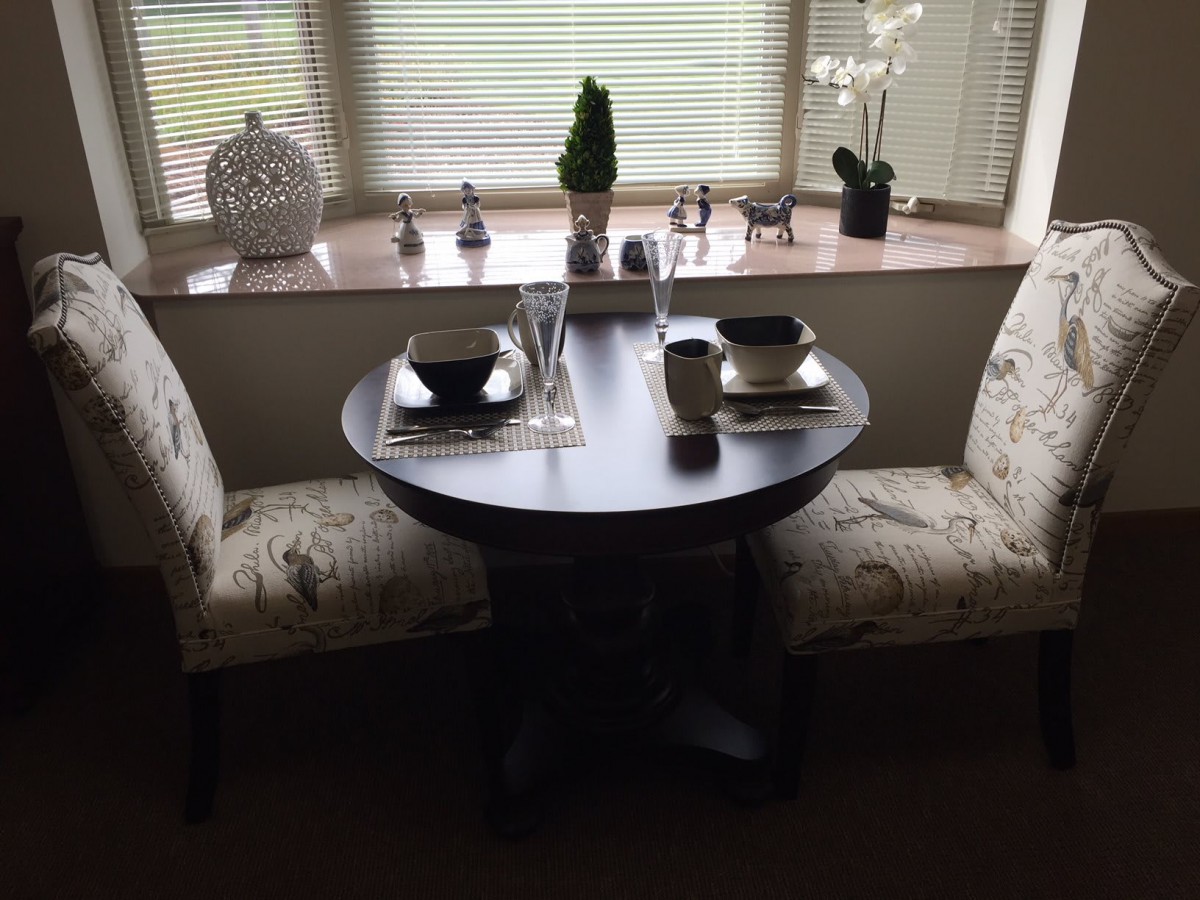 A small dining table set for two with decorative accents by the window.