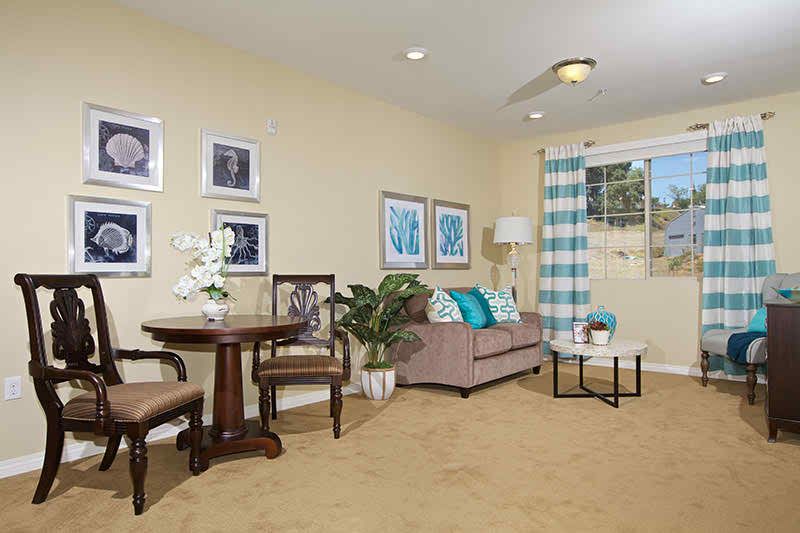 A cozy living room with a sofa, table, chairs, and decorative artwork on the walls.