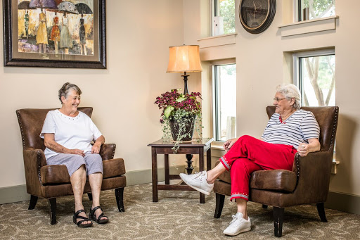 Two senior women engaged in a friendly conversation in a cozy indoor setting.