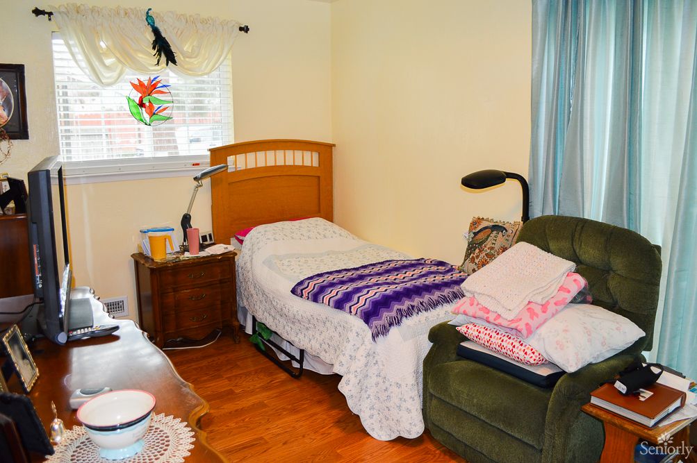 A cozy bedroom with a single bed, armchair, and side table.