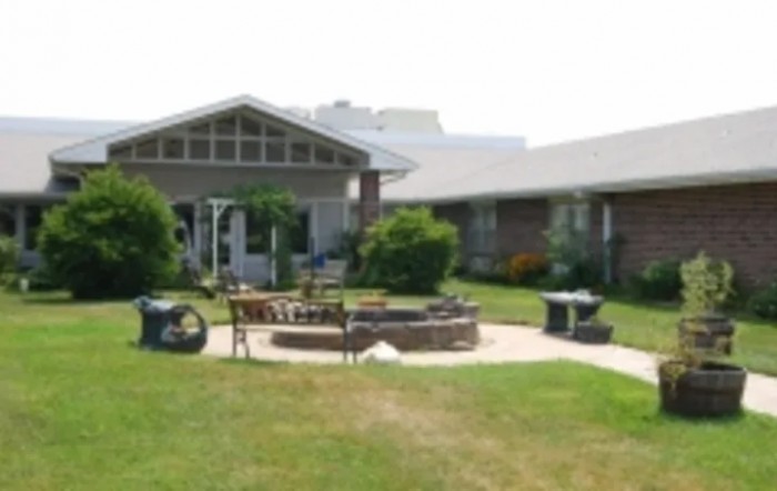 A well-maintained garden area with a circular patio and outdoor seating in front of a house.