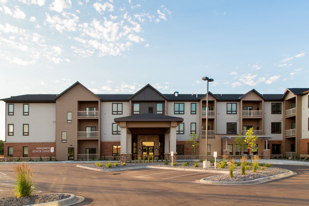 A modern residential apartment building with a large entrance and clear skies.