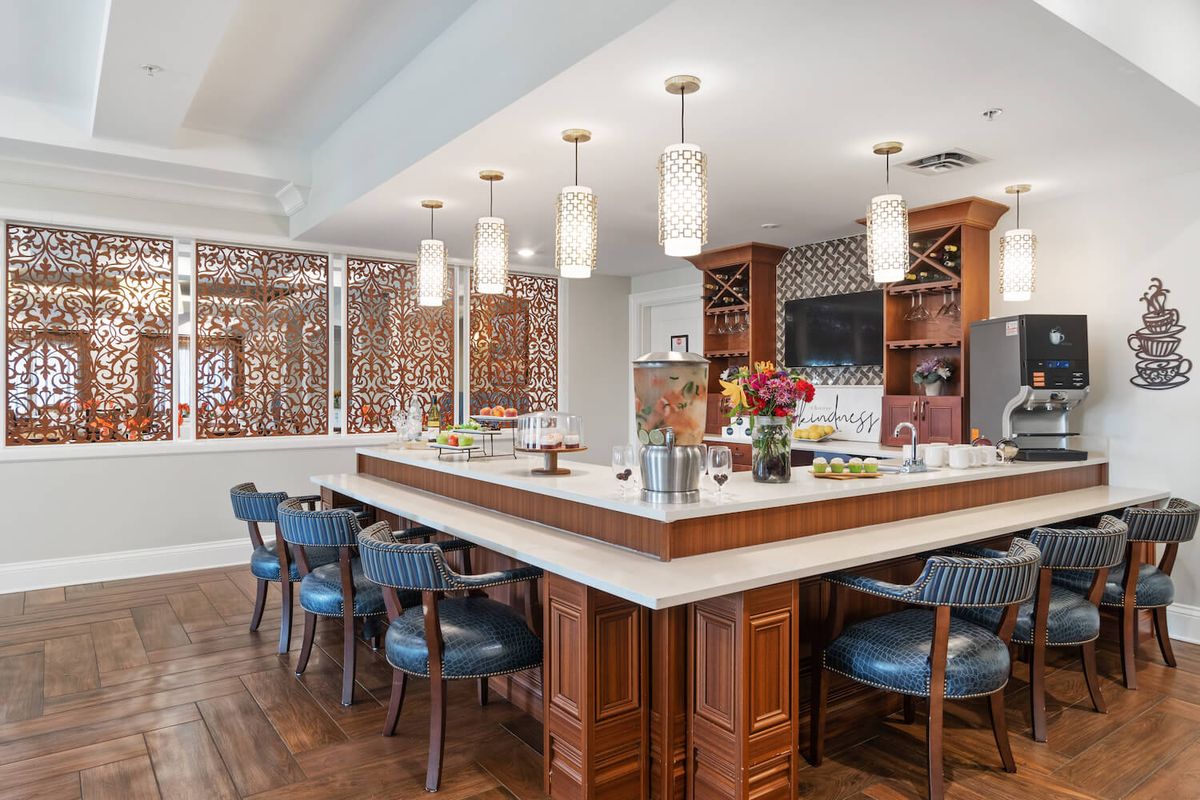 A modern kitchen and dining area featuring a large bar with pendant lighting, wooden cabinetry, and ample seating.
