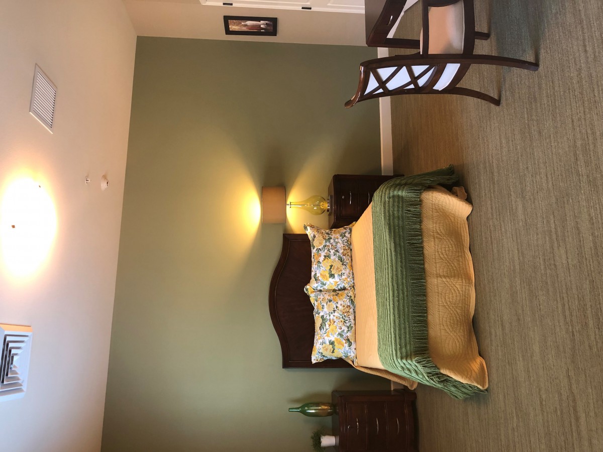 A cozy bedroom with a green accent wall and warm lighting.