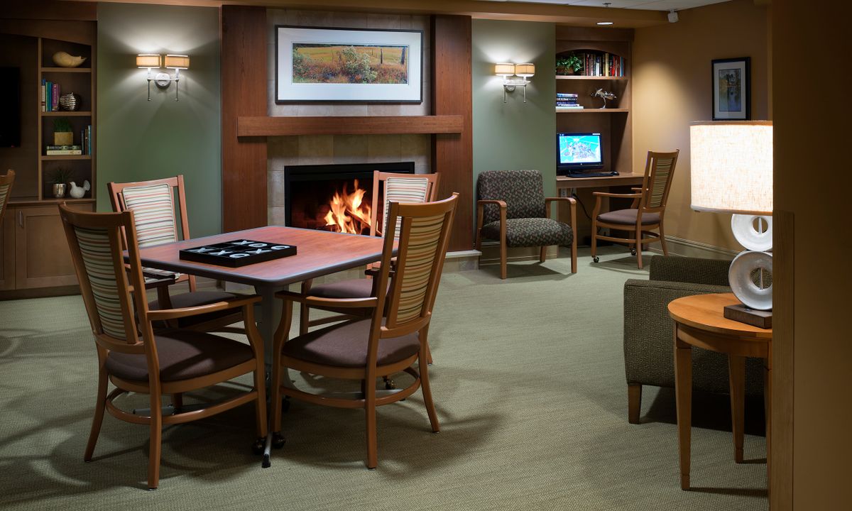 A cozy lounge area with a fireplace, seating, and computer stations.