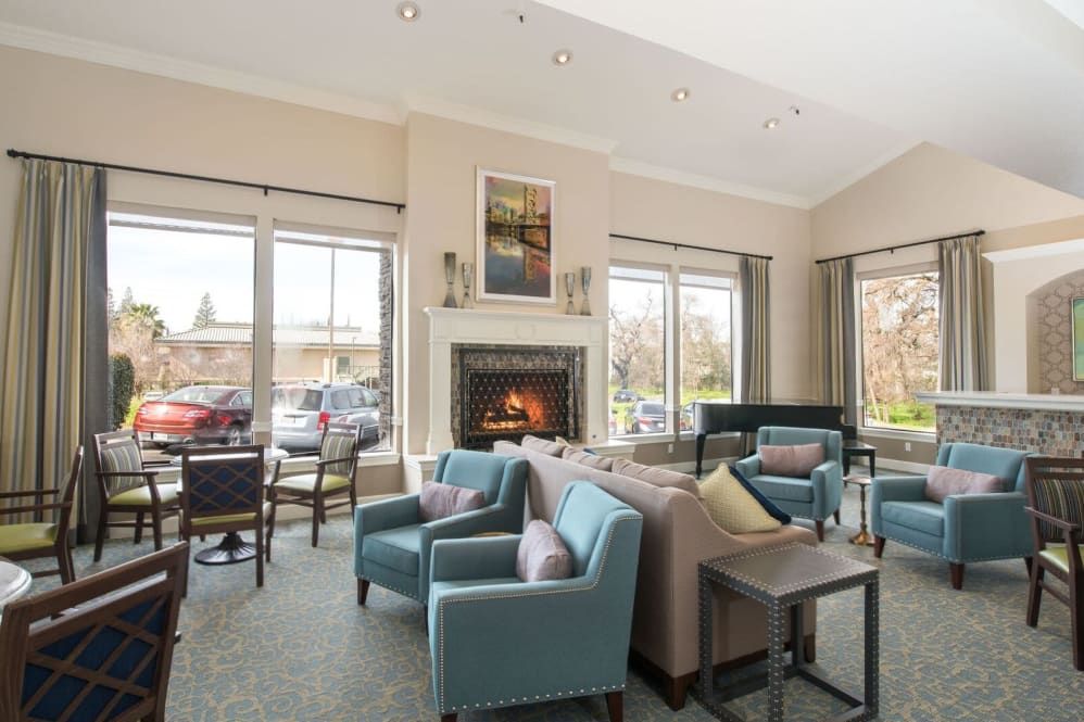 A cozy living room with modern decor, featuring a fireplace and ample seating around a central area.