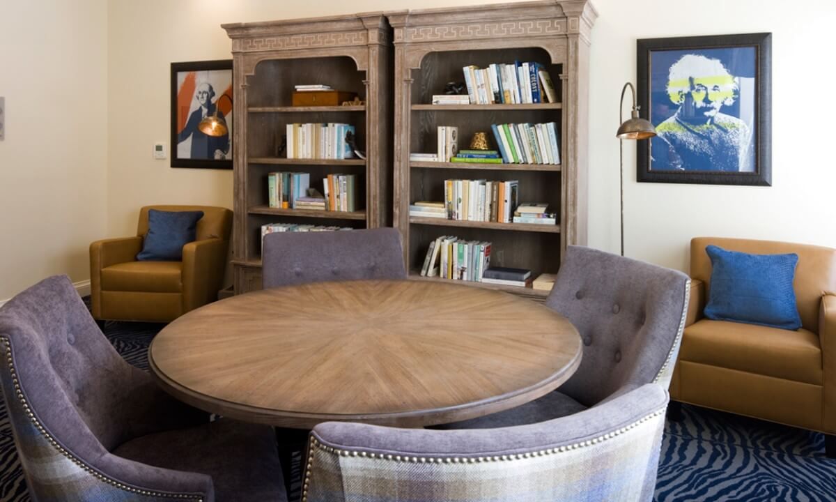 A cozy reading area with bookshelves, a round table, and comfortable chairs.