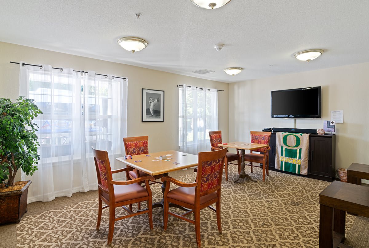 A well-lit dining area with a table, chairs, and a television.