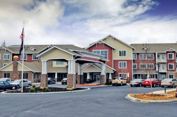 A mid-sized hotel with an inviting entrance and a parking lot under a cloudy sky.