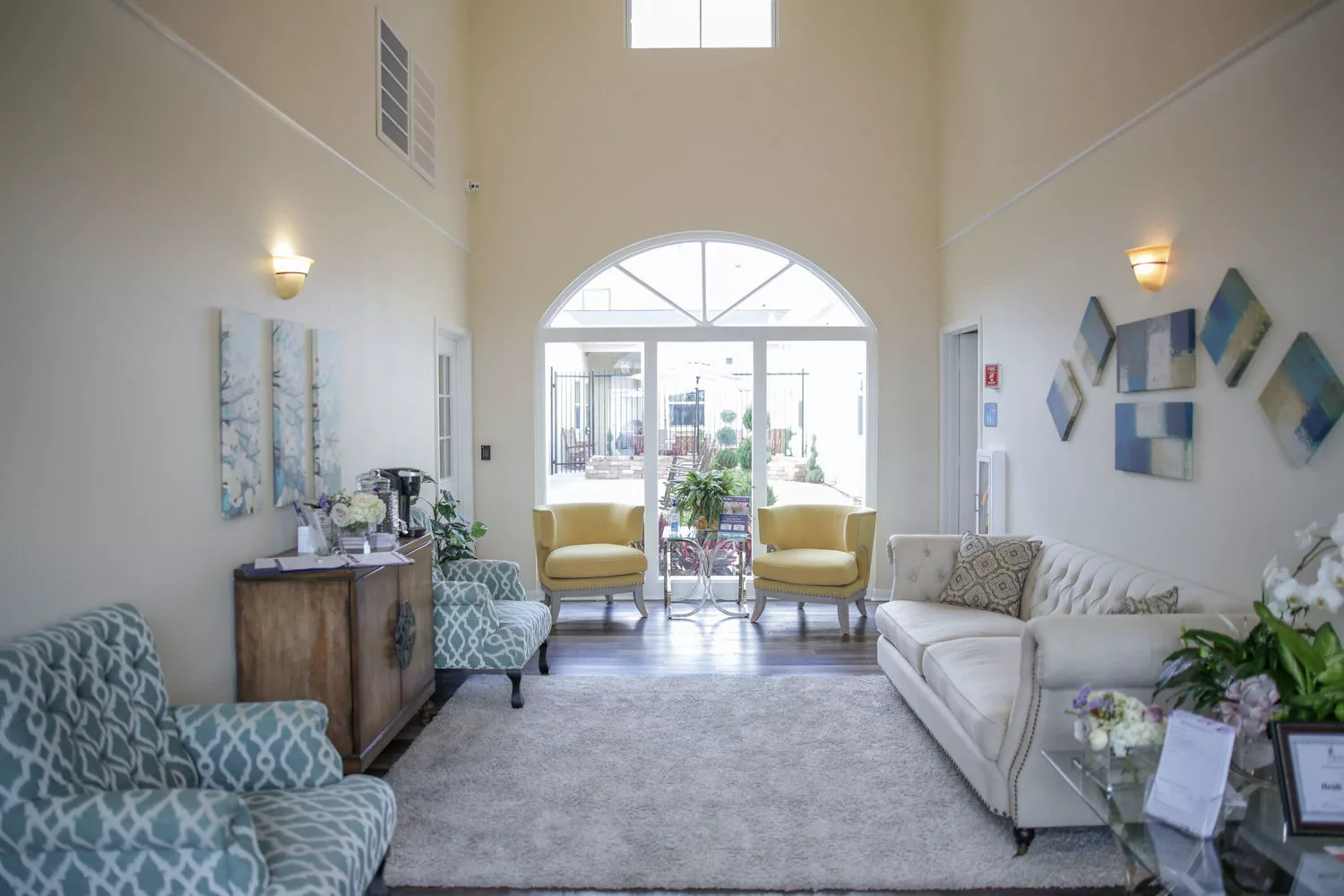 A spacious living room with elegant furniture, featuring a sofa, chairs, and large windows that let in natural light.