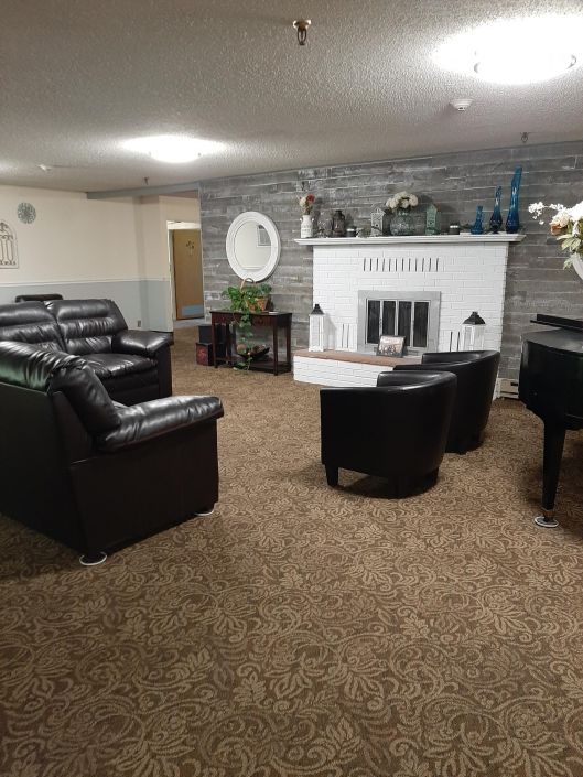 A cozy living room featuring leather sofas, a piano, and a fireplace.