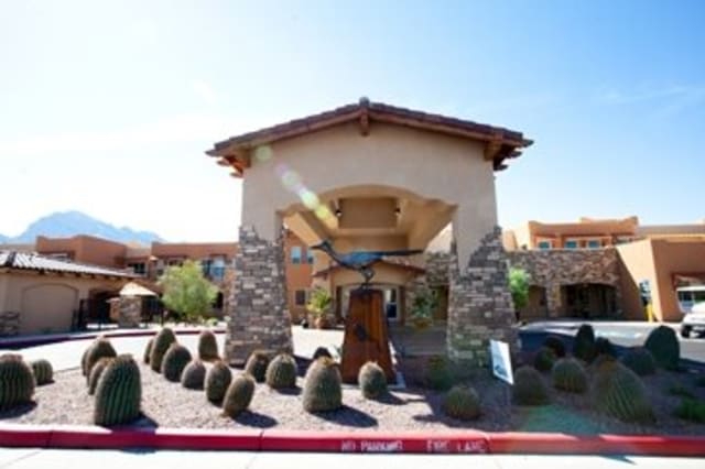 An entrance of a building featuring stone pillars and desert landscaping.