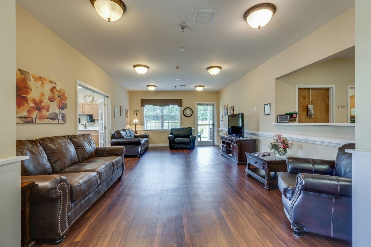 A spacious living room featuring leather sofas, hardwood flooring, and a television.